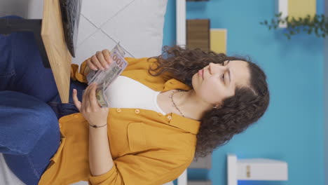 Vertical-video-of-Young-woman-looking-at-laptop-counting-money.